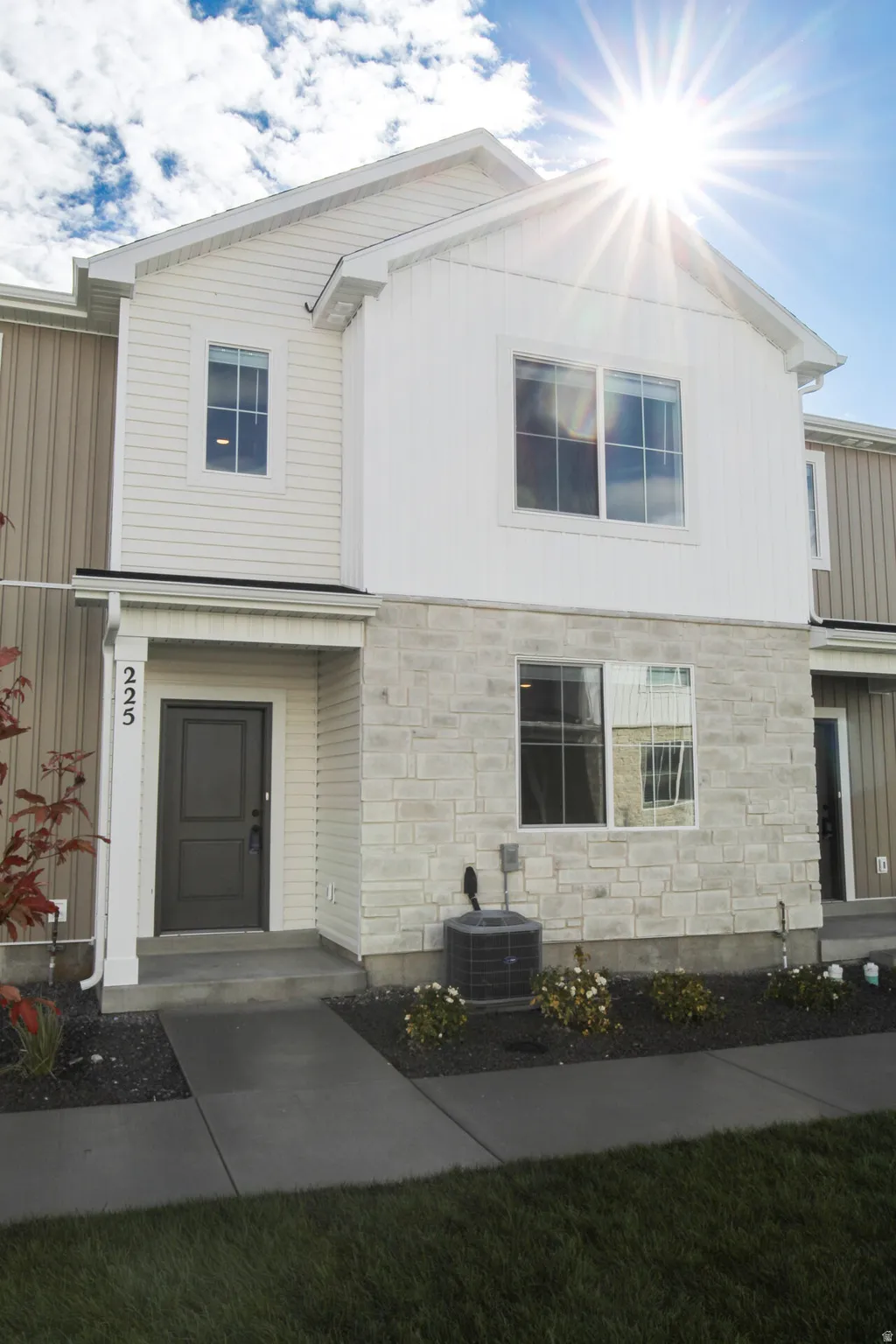 Contemporary townhome exterior featuring light-toned siding and a stone facade