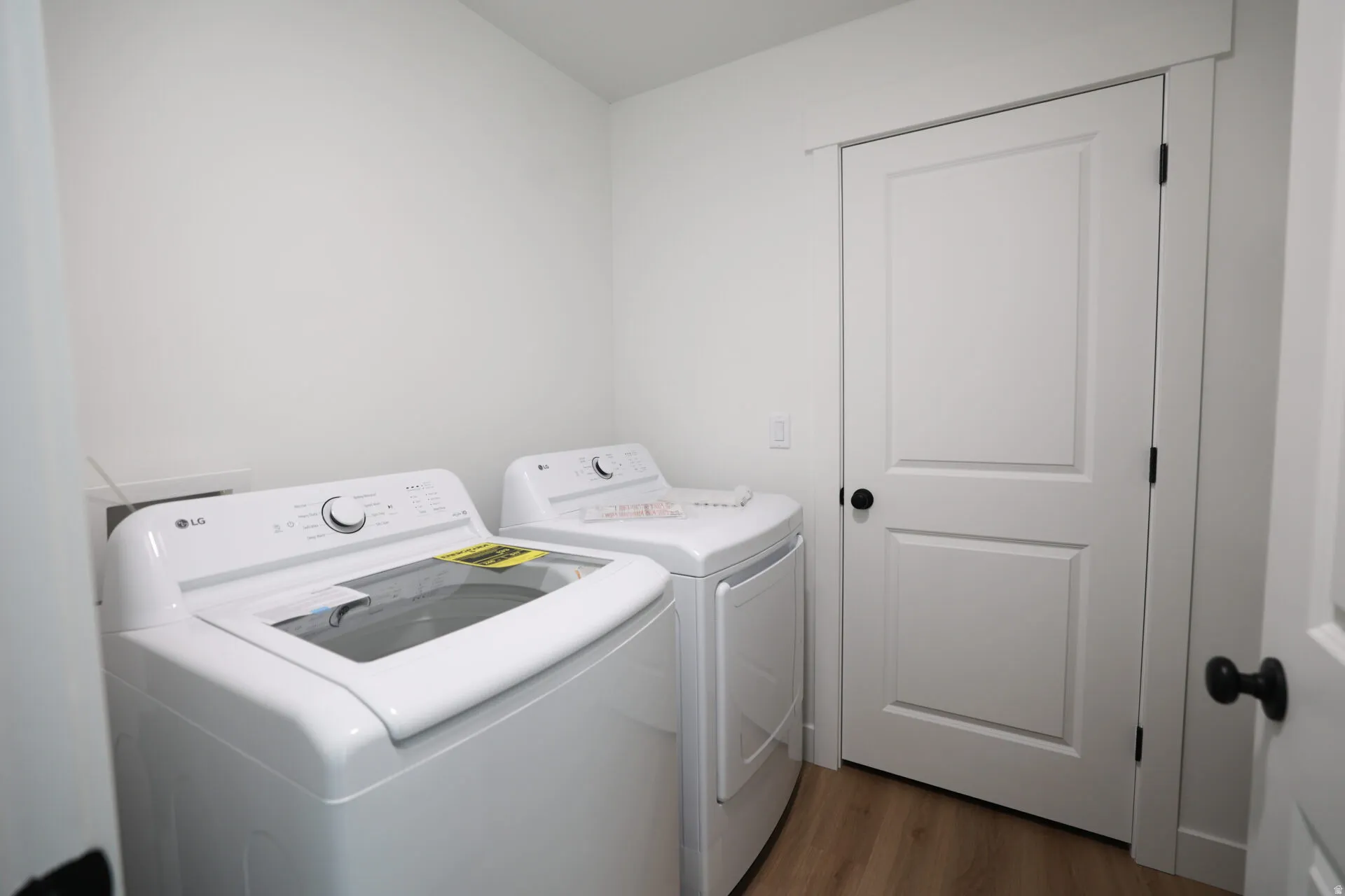 Dedicated laundry area featuring wood-finish flooring and bright white walls