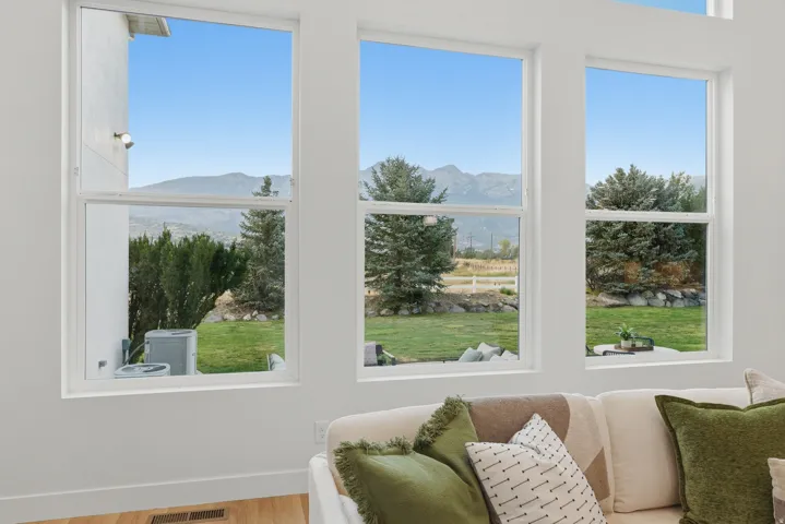 Spacious living area featuring large windows, white trim, and wood-finish flooring