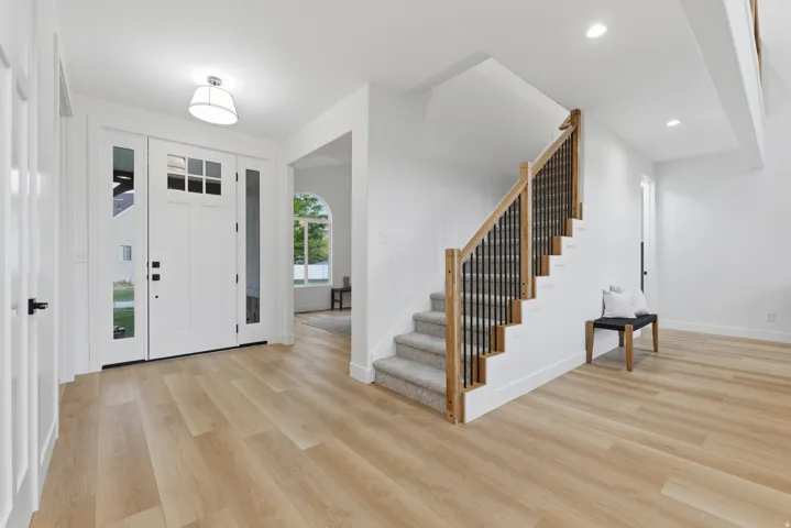 Bright entryway featuring wood-finish flooring and a white front door with sidelights