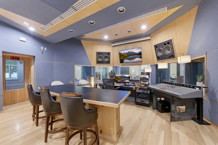Professional recording studio with acoustic paneling, wood-finish flooring, recessed lighting, and integrated sound equipment