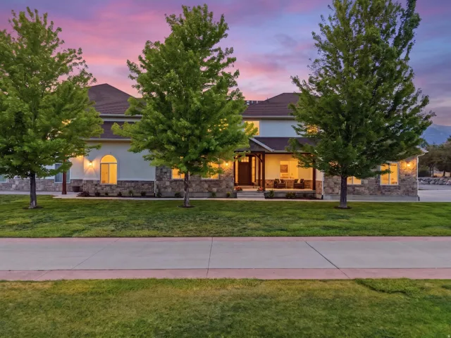 Stucco and stone exterior featuring a covered front porch, arched windows, and a concrete paver walkway