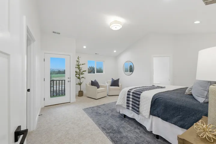 Spacious bedroom featuring light-toned carpeting, a vaulted ceiling, and recessed lighting