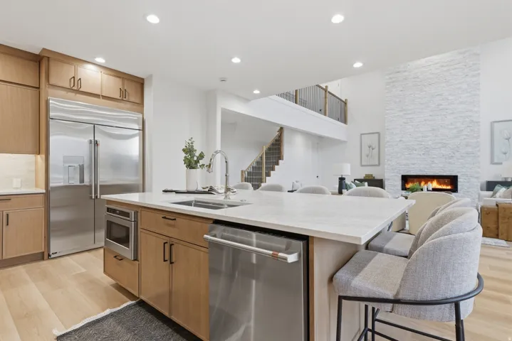 Open-concept kitchen with a large island featuring a sink, stainless steel dishwasher, and built-in microwave