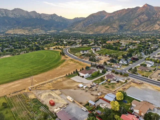 Expansive rural-urban landscape featuring distant mountains, a curved roadway, and residential properties with varied rooflines