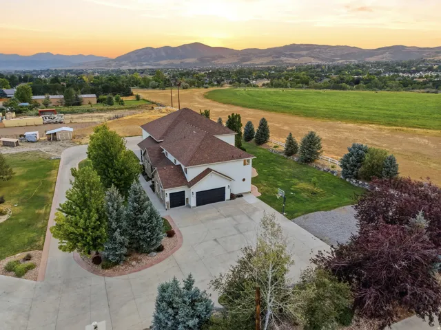 Two-story residence with a multi-car garage, expansive concrete driveway, and mature landscaping