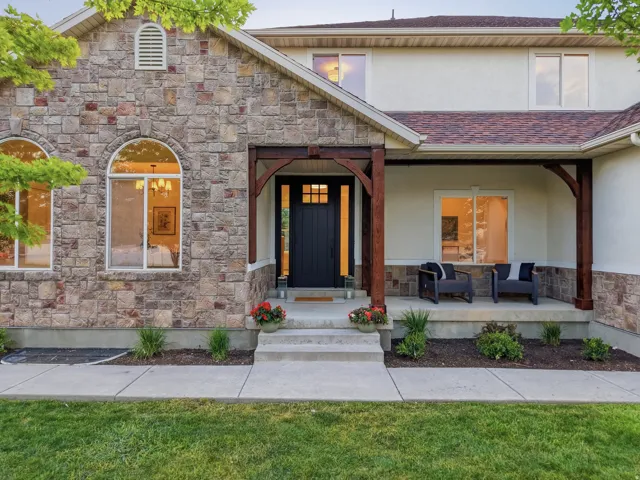 Stone veneer and stucco exterior with a covered entry porch featuring decorative wood beams