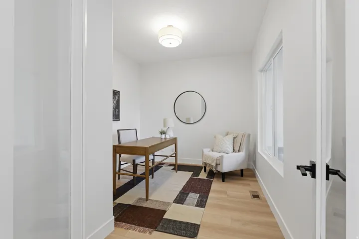 Bright room featuring light wood-finish flooring, white walls, and a contemporary flush-mount ceiling light