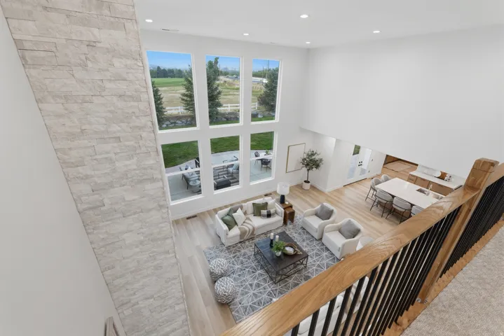 Open-concept living area with a stone-clad accent wall, soaring ceilings, and expansive windows