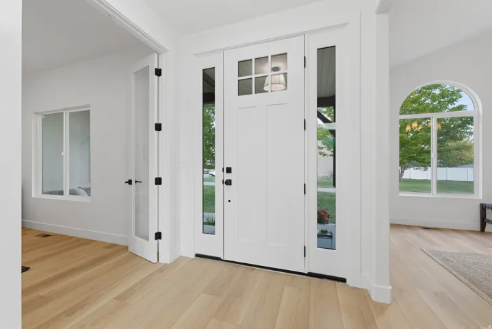 Entryway with wood-finish flooring, a white paneled front door with glass inserts, and two clear glass sidelights