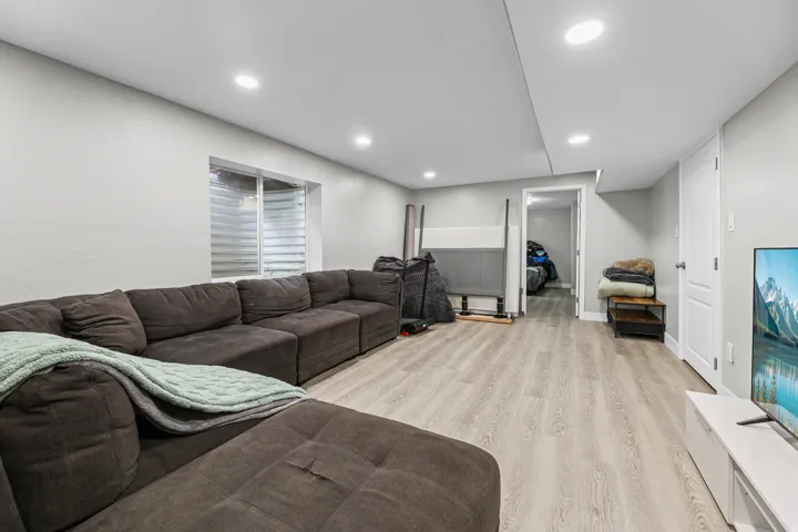 Spacious room with light wood-finish flooring, recessed lighting, and a white interior door