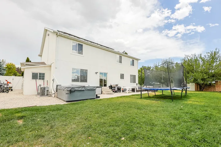Expansive backyard with a manicured lawn, dedicated gravel area, and mature trees