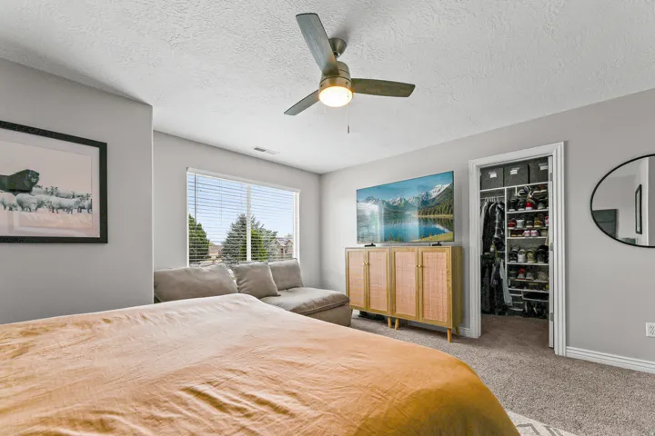 Carpeted room featuring a ceiling fan with integrated lighting, a window with horizontal blinds, and a built-in closet with shelving