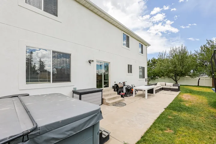 Expansive backyard featuring a concrete patio, mature trees, and a spacious lawn