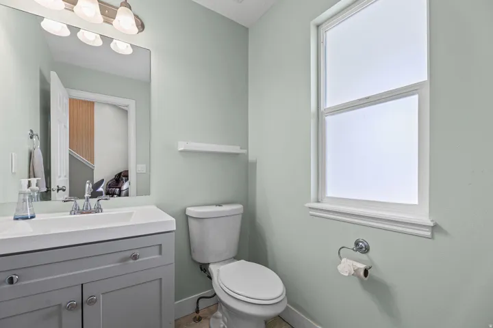 Bathroom featuring a light-colored vanity with an integrated sink and chrome faucet, a rectangular mirror, and a window with white trim