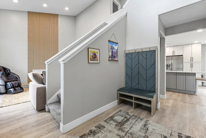 Entry foyer featuring wood-finish flooring, a built-in bench with upholstered backing, and a staircase with carpeted treads