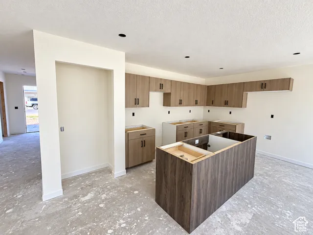 Kitchen featuring wood-finish cabinetry, a central island, and recessed lighting-under construction