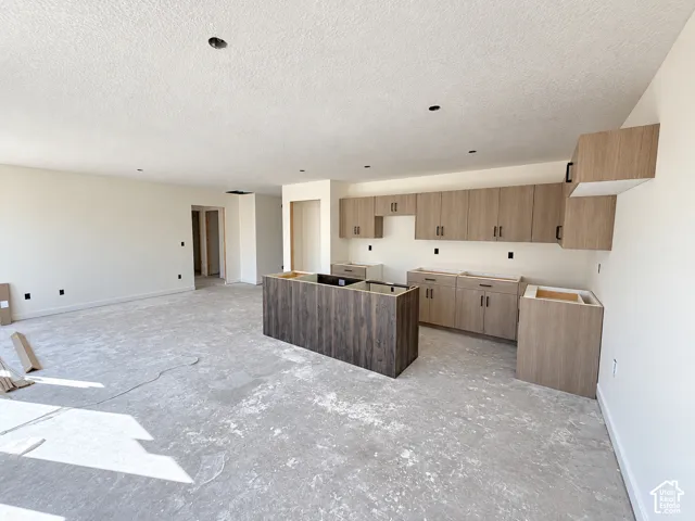 Kitchen featuring a wood-finish island, light wood-finish cabinetry, and recessed lighting-under construction