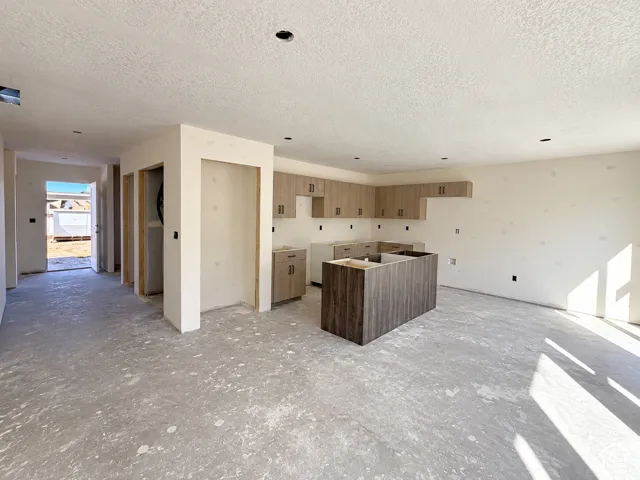 Open-concept kitchen with wood-finish cabinetry, a large central island, and recessed lighting under construction