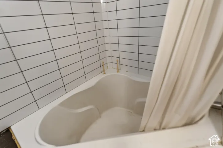 Corner tub with white subway tile surround and brass fixtures