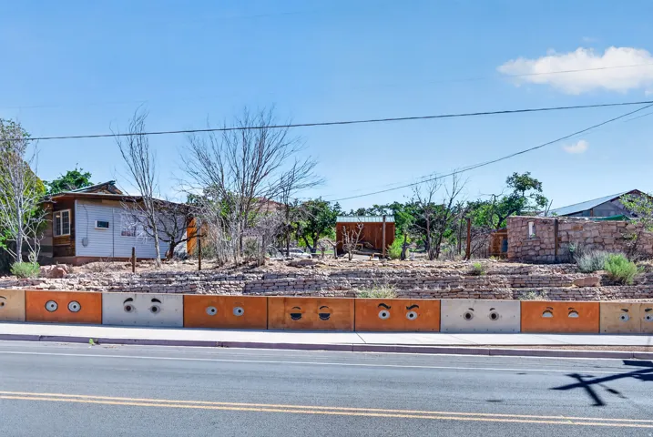 Street-facing retaining wall with custom painted concrete blocks and a stone-clad upper section