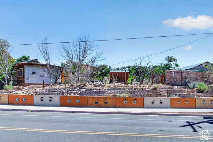 Street-facing retaining wall with custom painted concrete blocks and a stone-clad upper section