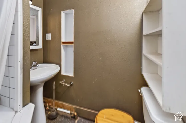 Pedestal sink with chrome faucet, framed wall mirror, and built-in wall niche with wood-finish shelf