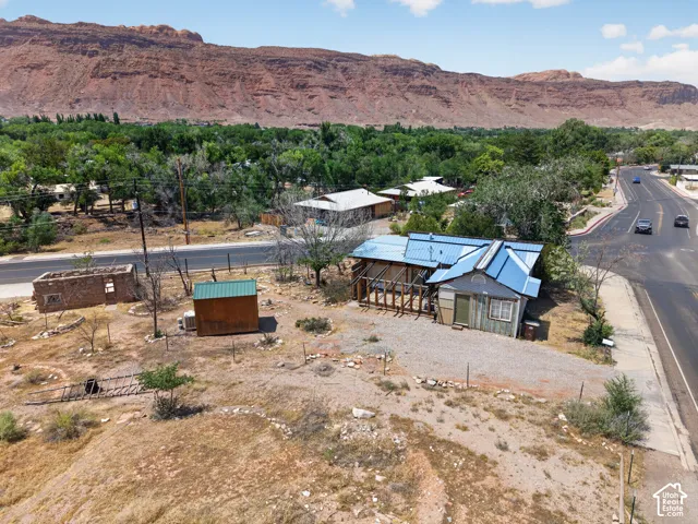 Property featuring a blue metal roof, gravel driveway, and an adjacent paved road