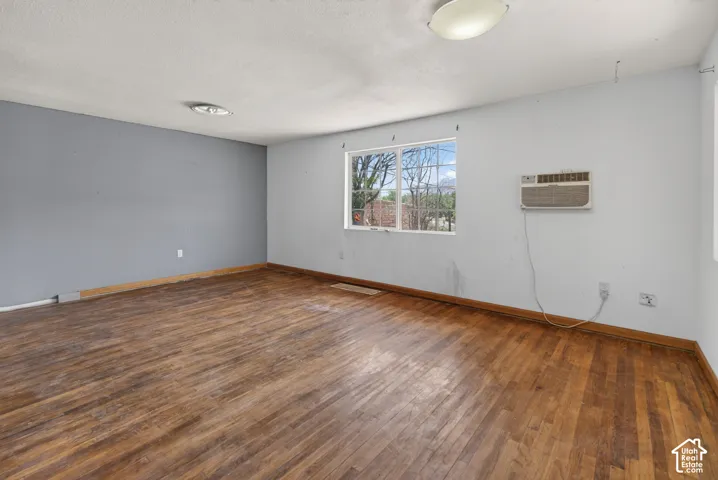 Spacious room featuring wood-finish flooring, ample natural light from a rectangular window, and a ceiling-mounted light fixture