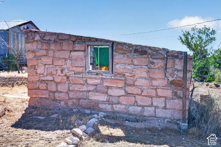 Stone wall structure featuring a window opening and surrounding natural vegetation