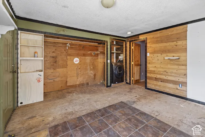 Room featuring partial wood-plank accent wall and tile flooring