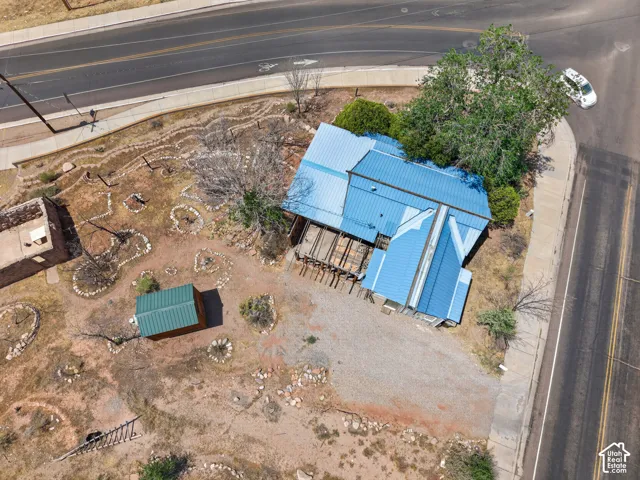 Property featuring a bright blue metal roof, an additional green metal-roofed structure, and a large shade tree