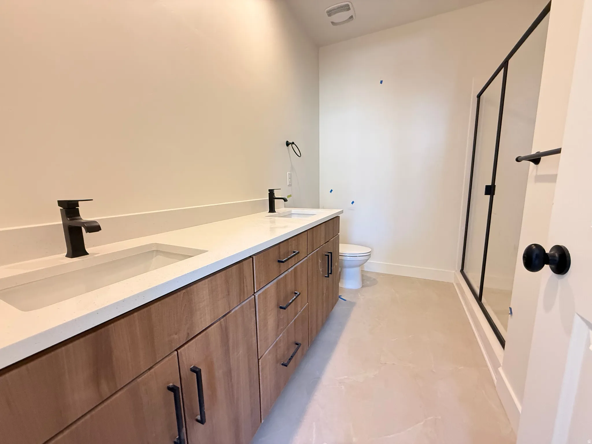 Dual sink vanity with wood-finish cabinetry, white countertop, and matte black fixtures