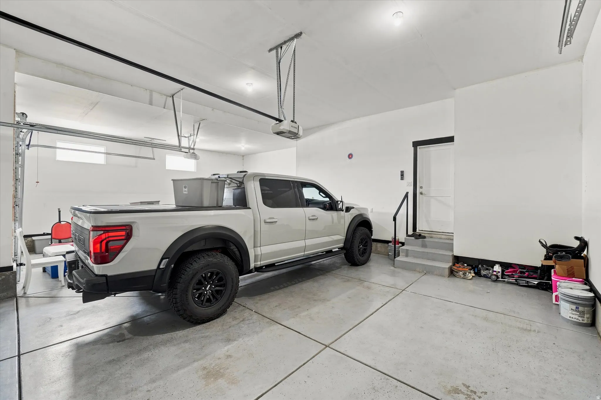 Attached garage featuring a concrete floor, white walls, and overhead lighting