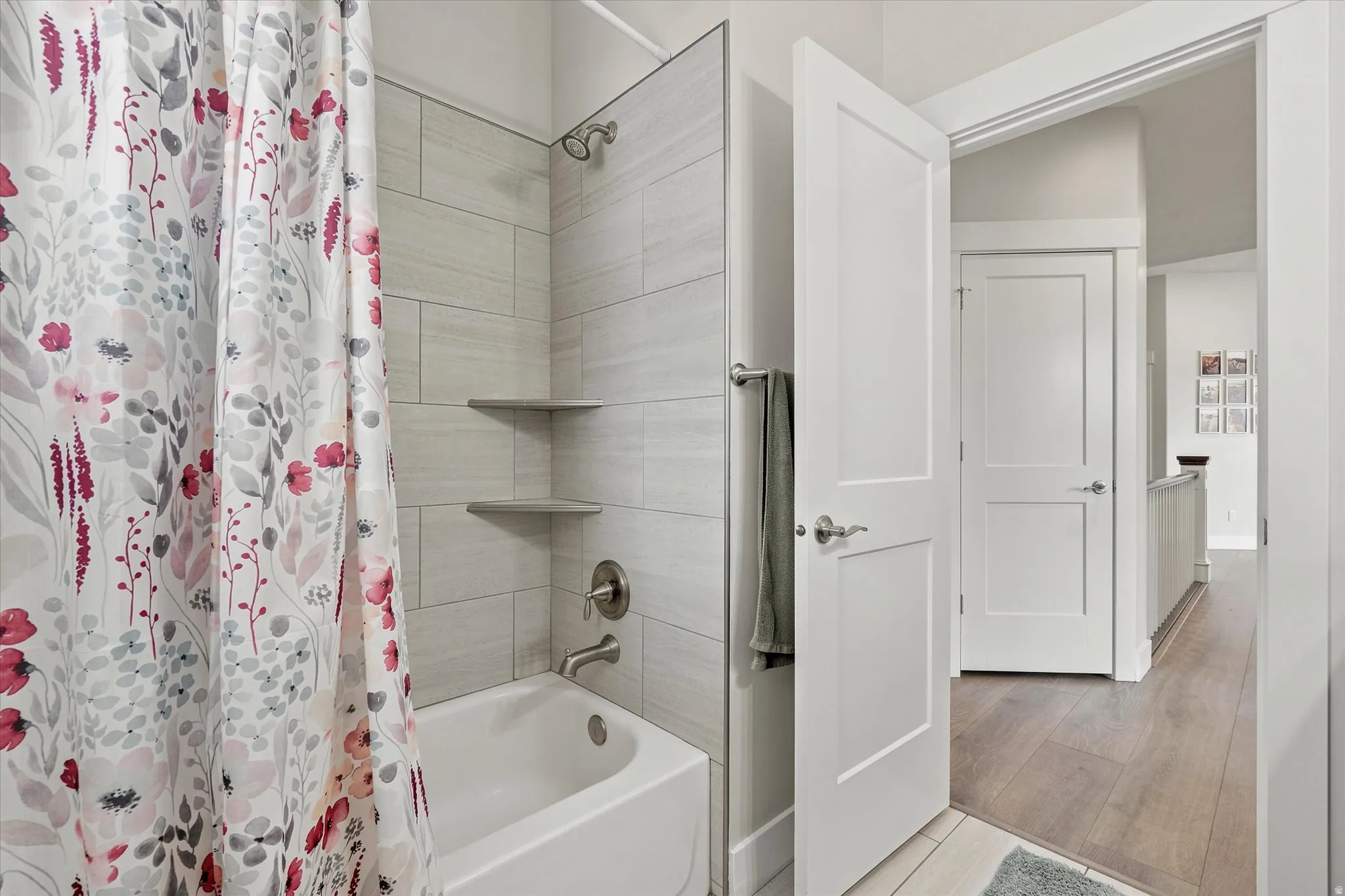 Bathroom featuring a full tub with brushed nickel fixtures, tiled shower surround, and built-in corner shelving
