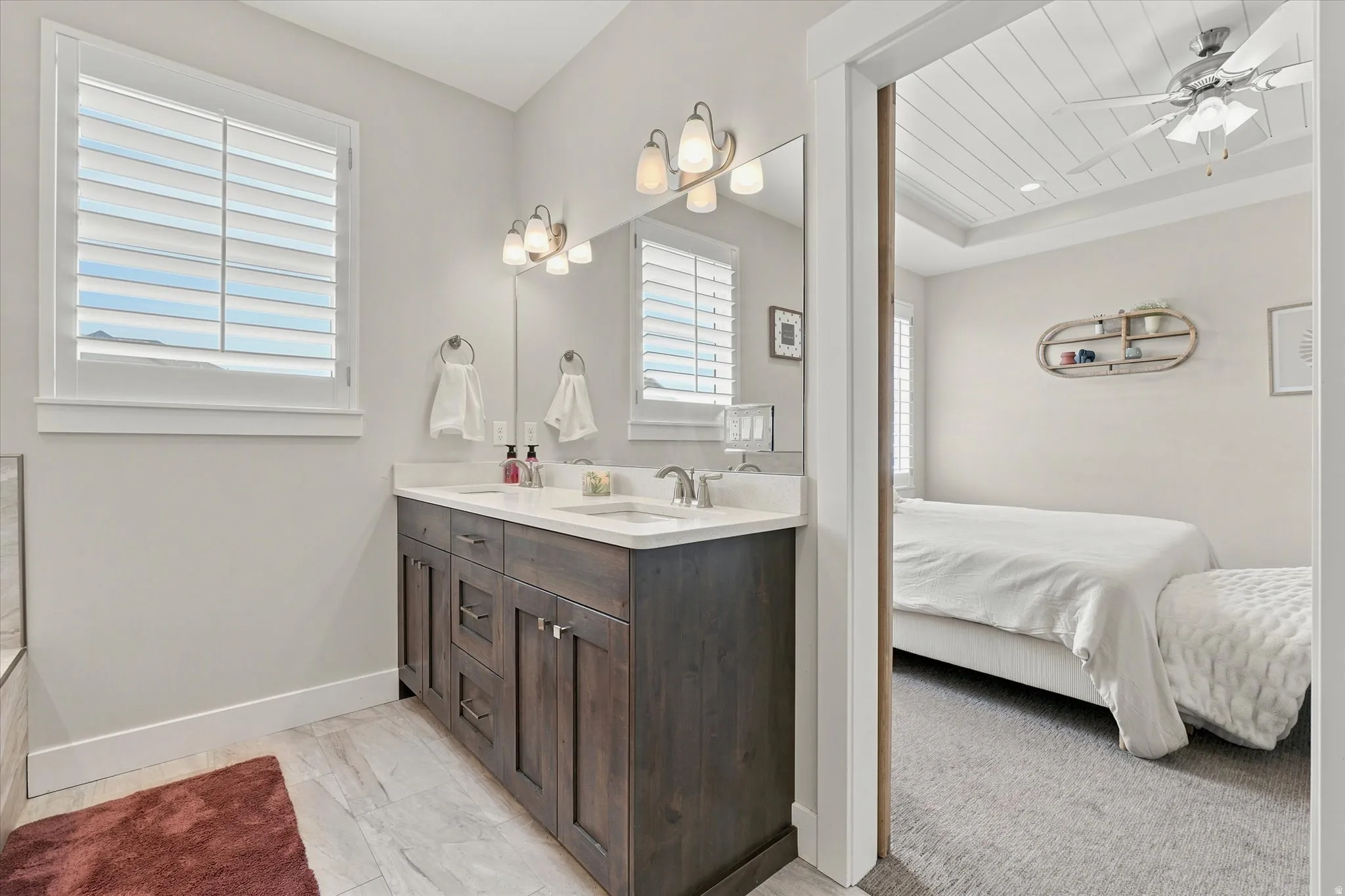 Bathroom featuring a double vanity with dark wood cabinetry, white countertops, dual undermount sinks, and polished chrome fixtures