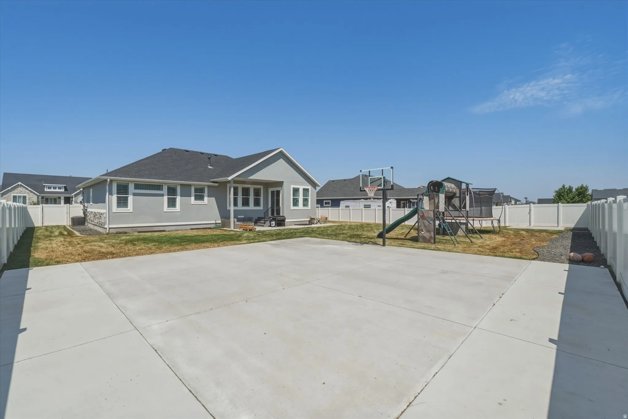 Expansive concrete pad suitable for recreation, bordered by a white privacy fence