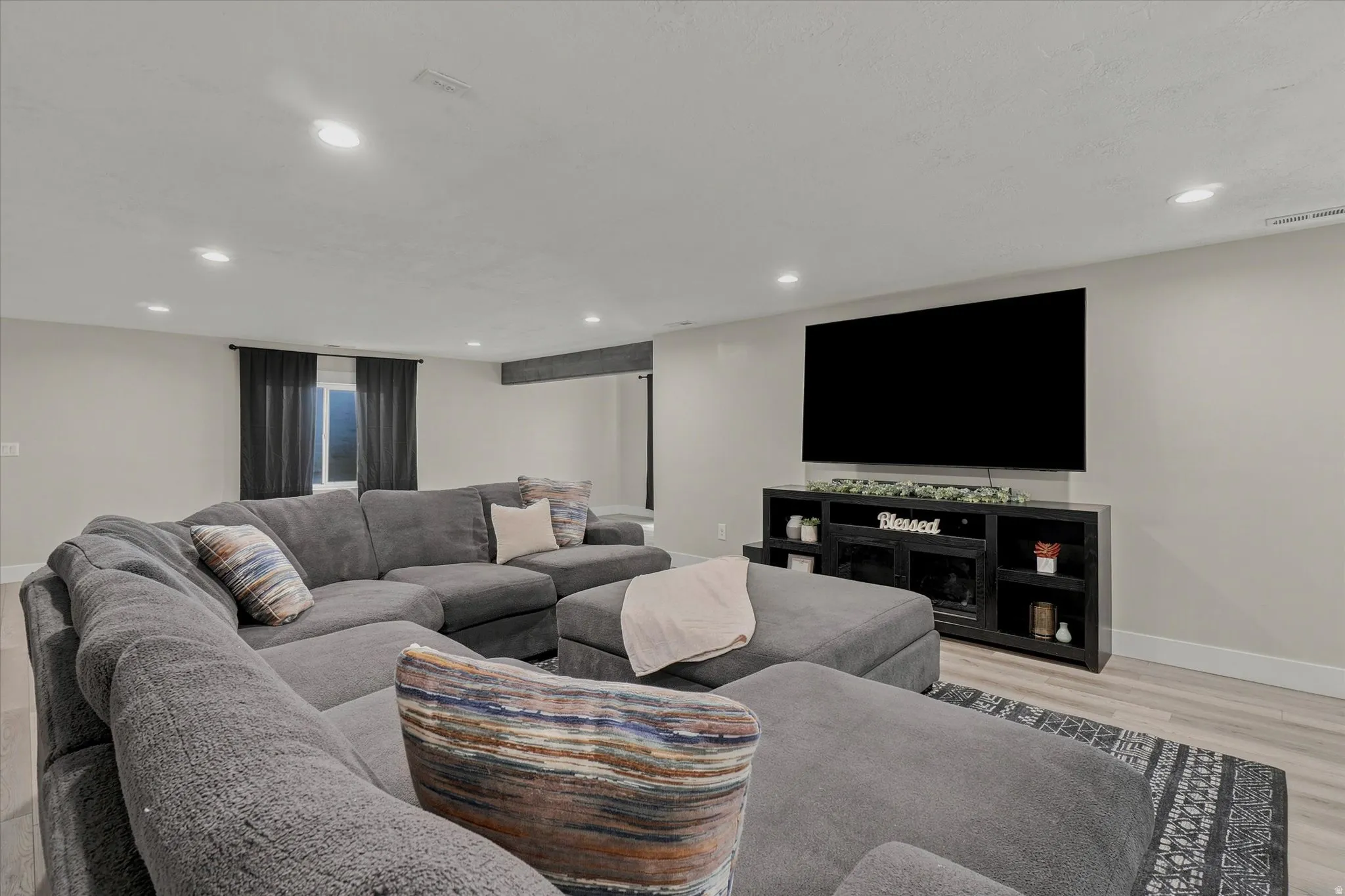 Spacious room featuring recessed lighting, light-toned walls, and wood-finish flooring
