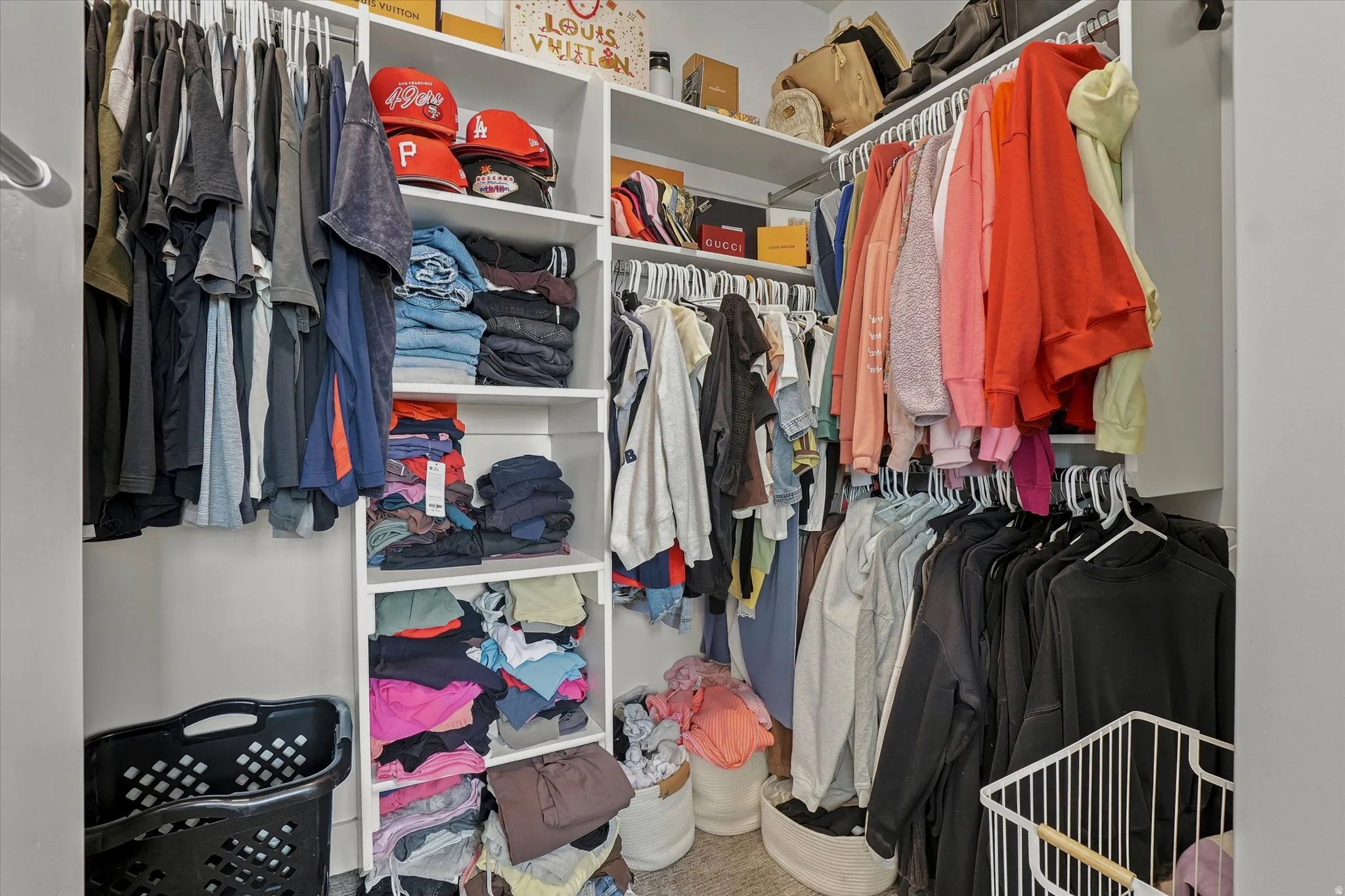Walk-in closet featuring white built-in shelving, multiple hanging rods, and ample storage space