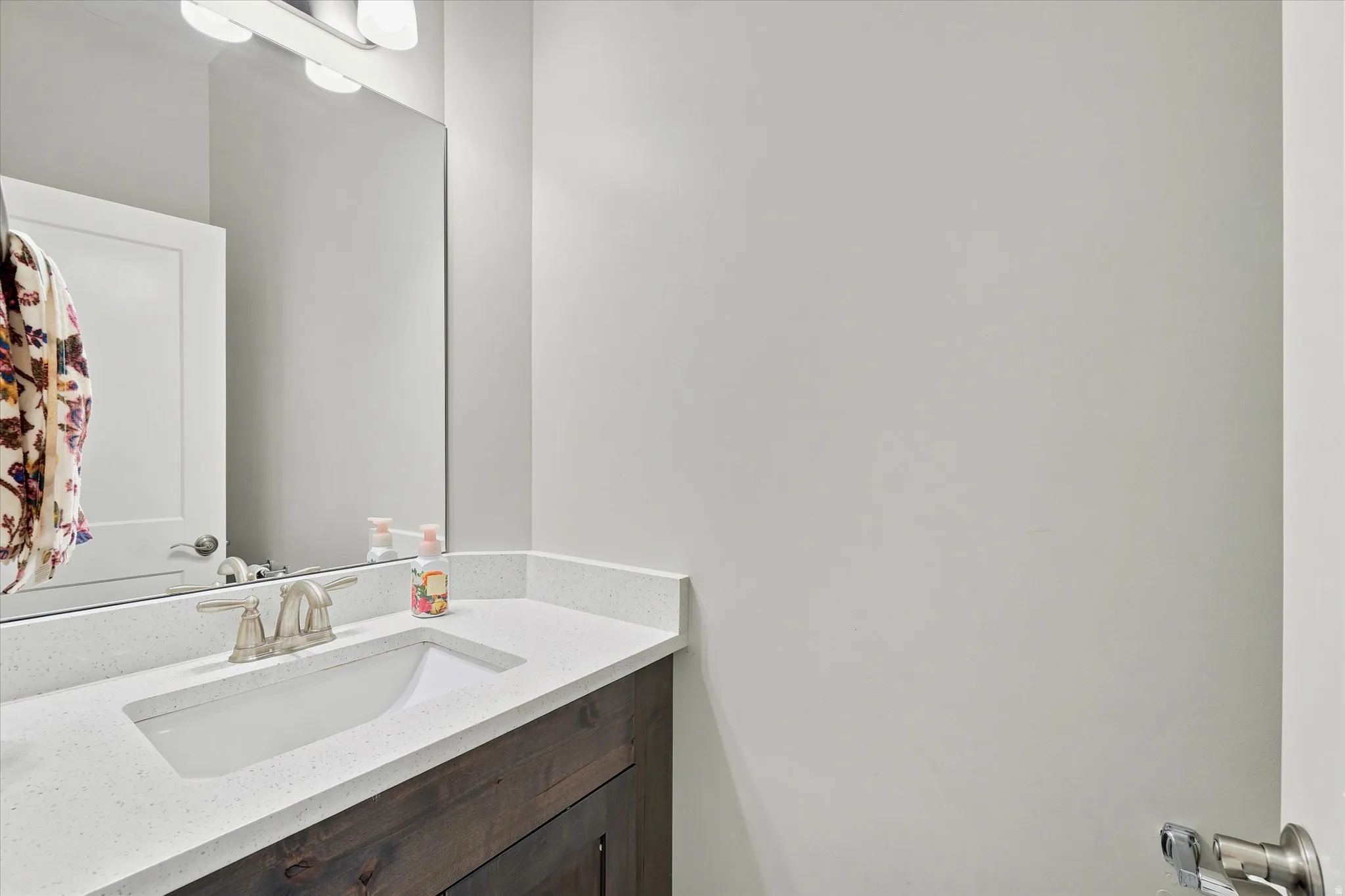 Bathroom vanity with a white rectangular undermount sink, brushed nickel faucet, and a light-toned countertop