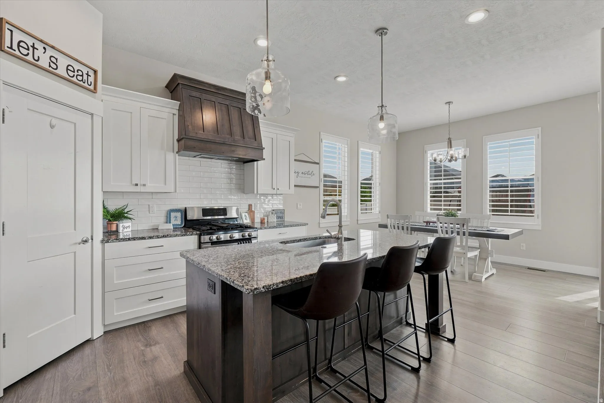 Open-concept kitchen featuring white shaker cabinetry, stainless steel appliances, and wood-finish flooring