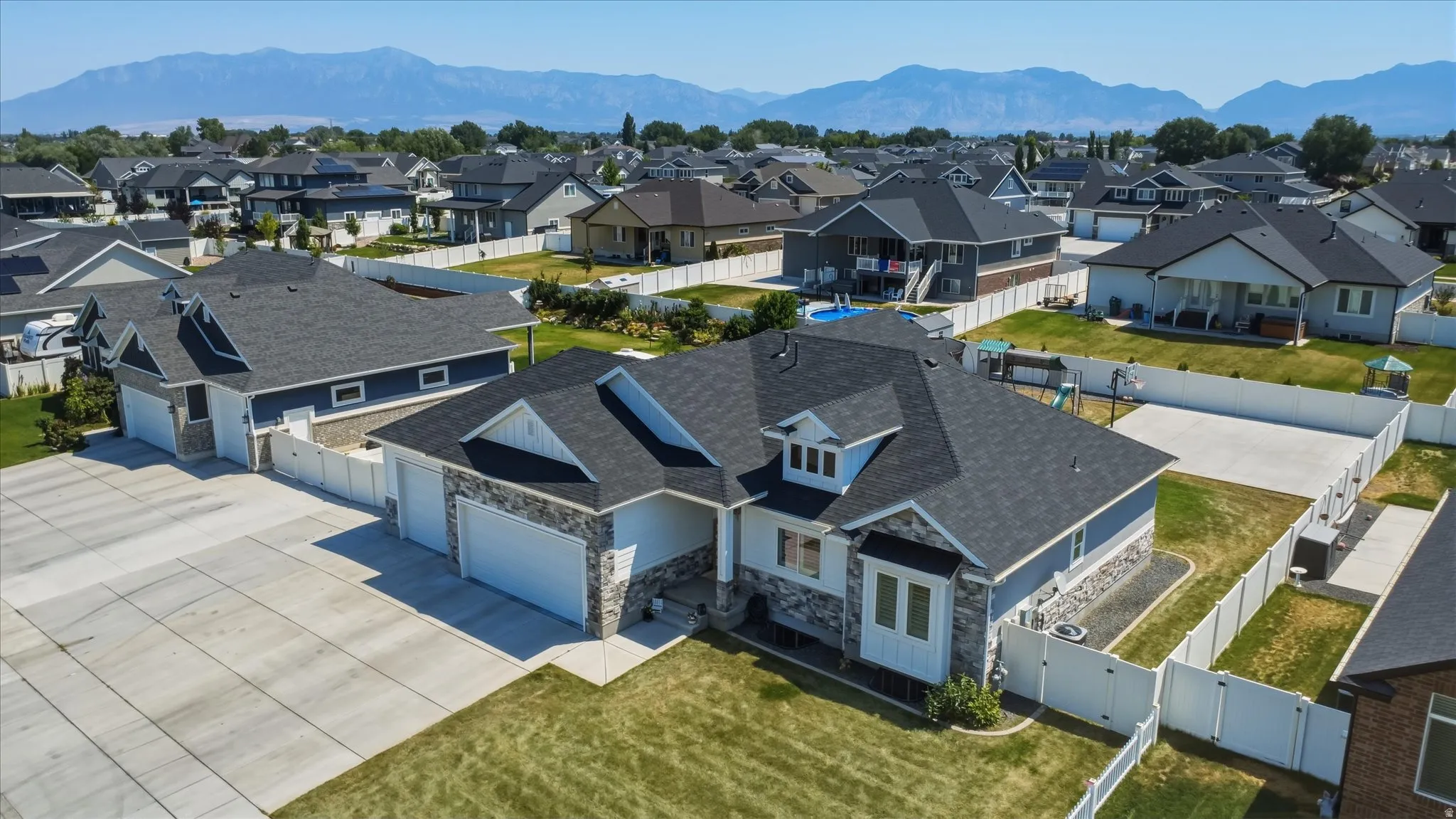 Contemporary residence featuring a stone facade, multi-car garage, and a large concrete driveway