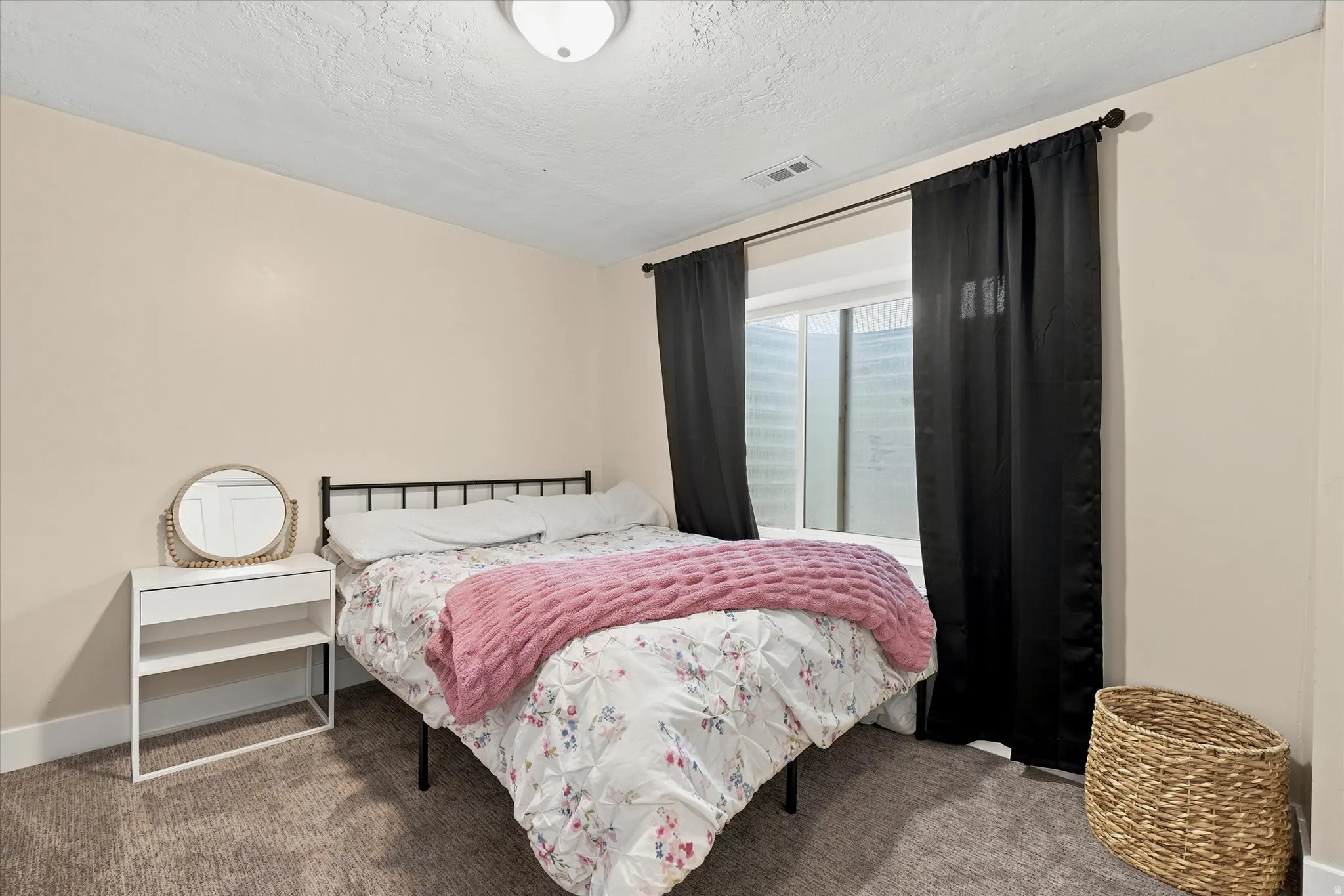 Carpeted room featuring a window with dark drapery, light-colored walls, and a flush-mount ceiling light fixture