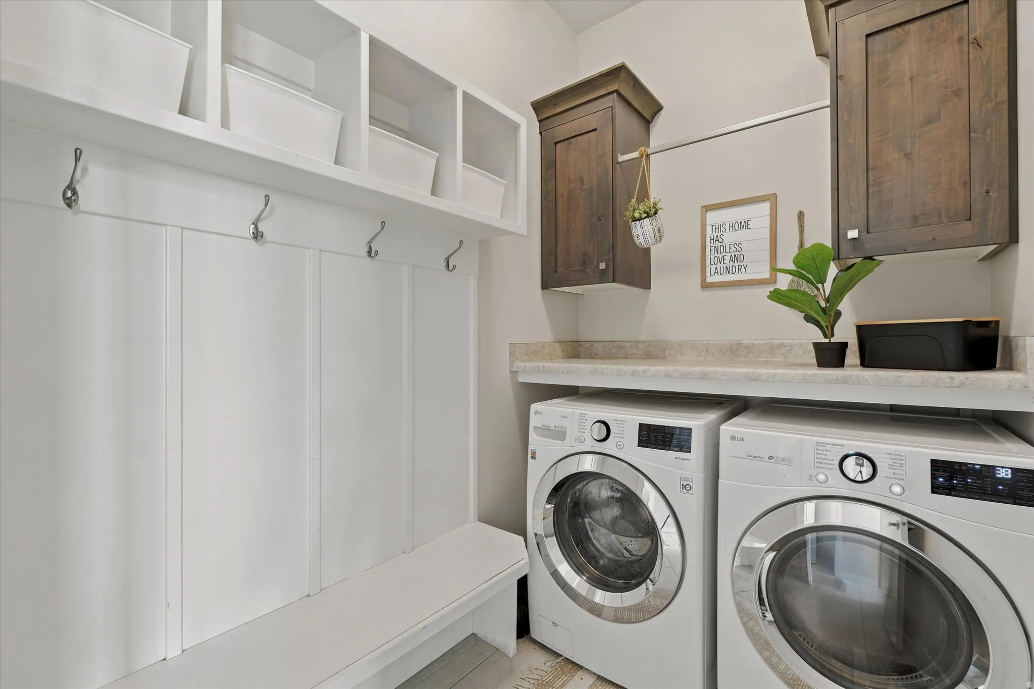 Dedicated laundry area featuring white shaker-style cabinetry, a built-in bench, and coat hooks