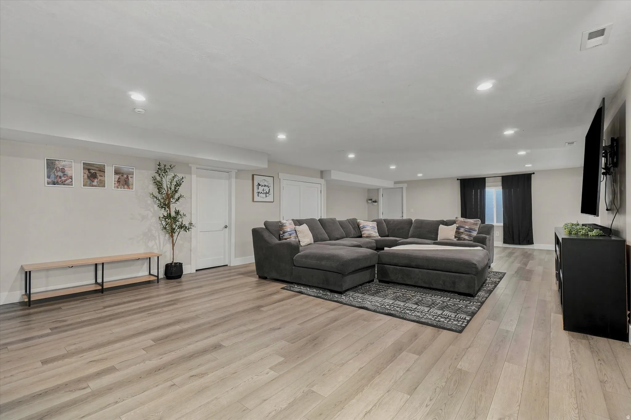 Spacious open-concept room featuring wood-finish flooring, recessed lighting, and neutral wall tones