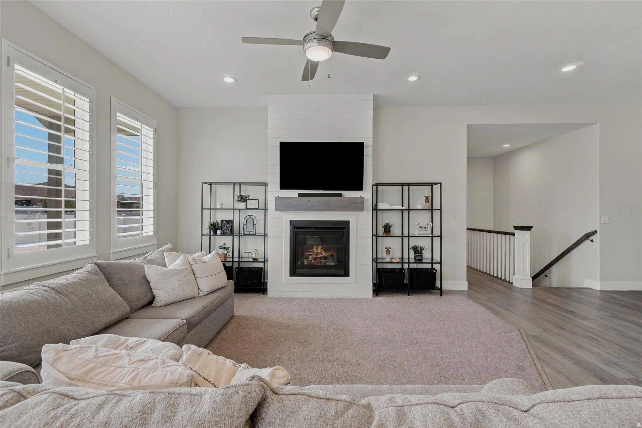 Living area featuring a fireplace with shiplap surround, a wood-finish mantel, and a ceiling fan