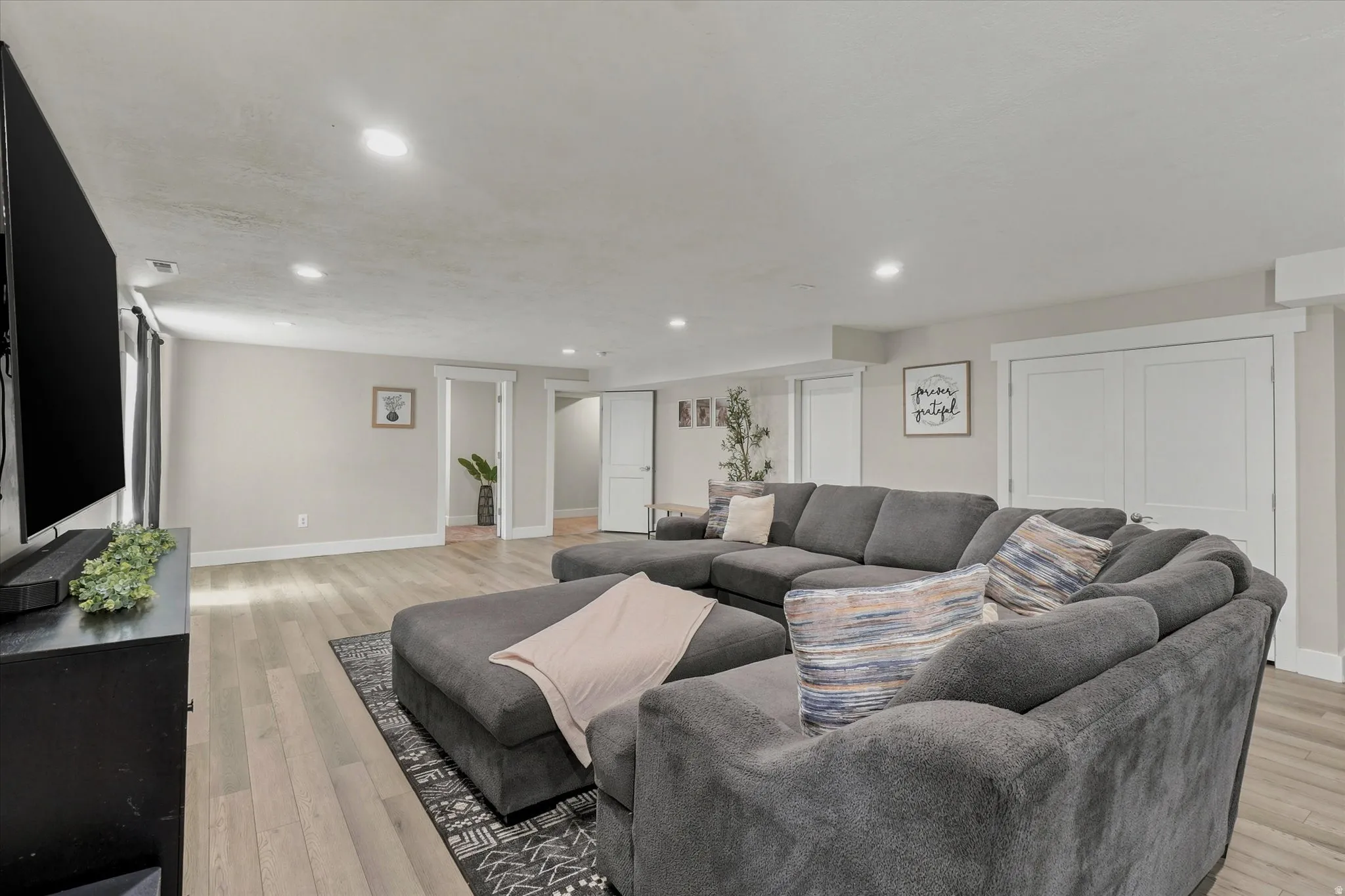 Spacious living area featuring light wood-finish flooring, recessed lighting, and neutral wall tones