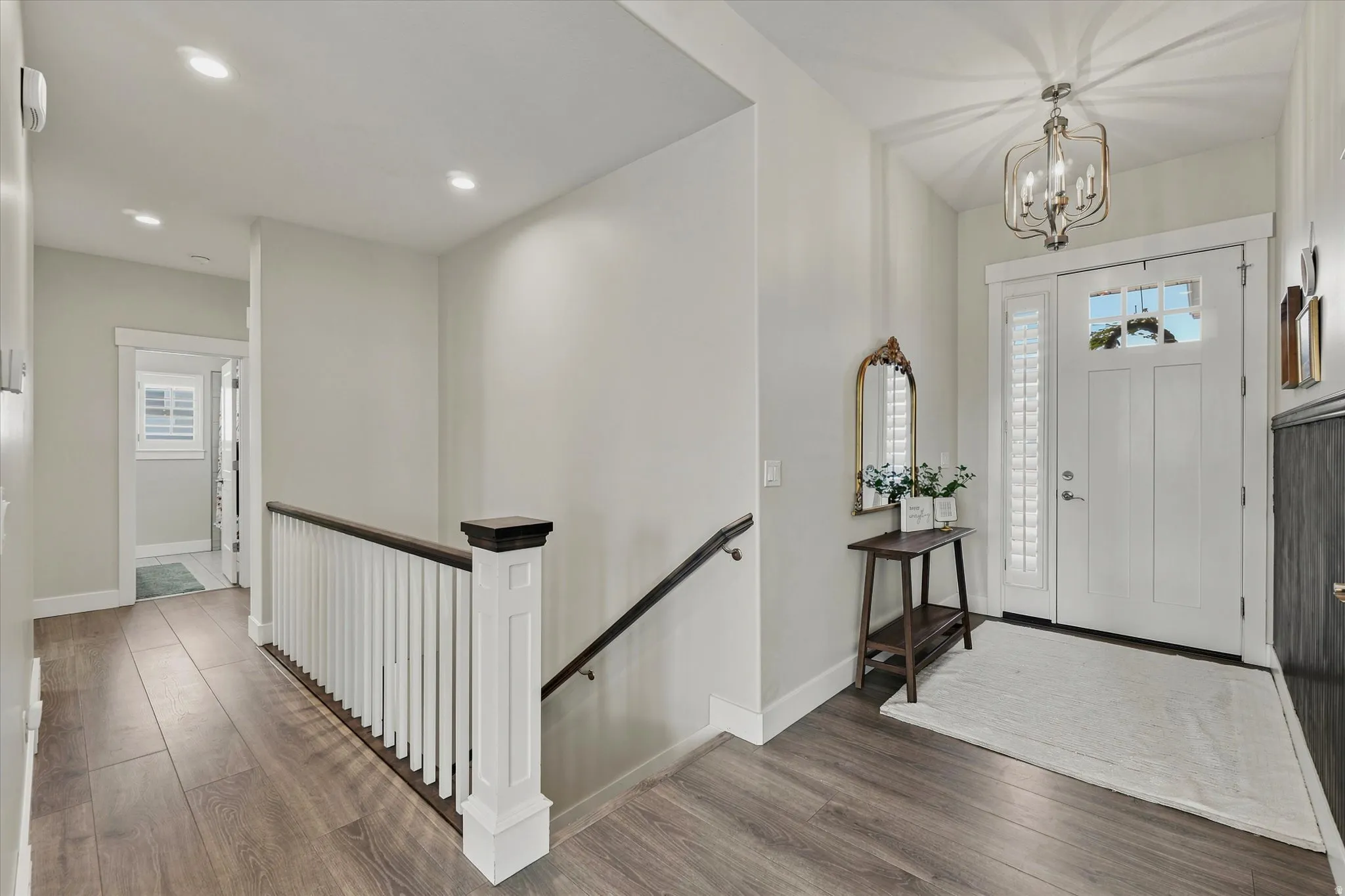 Entryway featuring a white paneled door with sidelights, wood-finish flooring, recessed lighting, and a chandelier