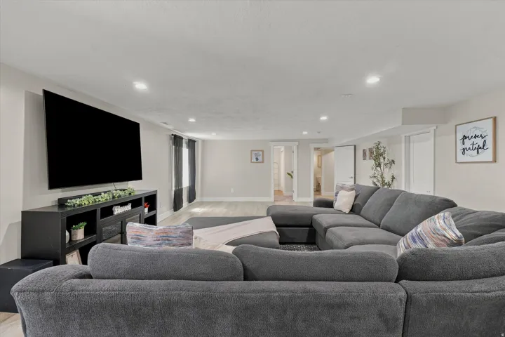 Spacious living area featuring light-toned walls, recessed lighting, wood-finish flooring, and white trim