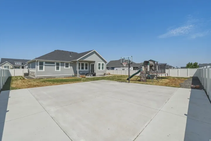 Expansive concrete pad suitable for recreation, bordered by a white privacy fence